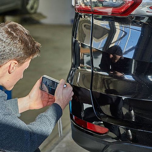 Mitarbeiter fotografiert Fahrzeug für Versicherung
