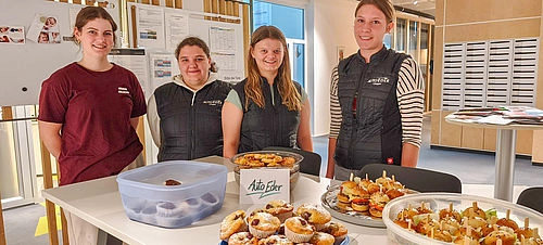 Mädchen stehen hinter dem Tisch gedeckt mit ihrem Essen 