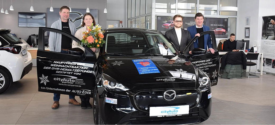 Gruppenfoto von Fahrzeugübergabe mit Geschäftsführern und dem Gewinnerpärchen.