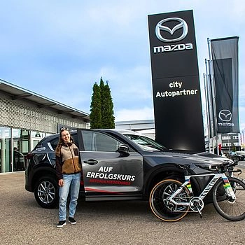 Antonia Niedermaier und ein Fahrrad vor dem Mazda 